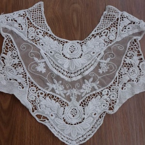 May include: White lace collar with intricate floral embroidery and a scalloped edge.