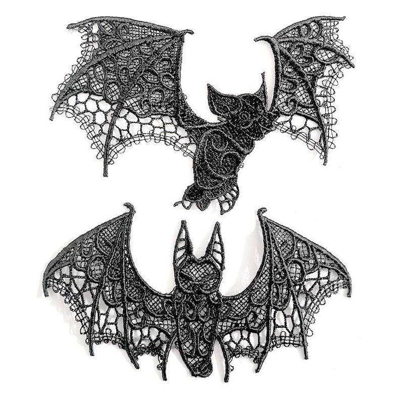 May include: Two black lace bat appliqu&eacute;s. One bat is in flight, the other is shown with its wings spread. The bats have detailed wing patterns and are set against a white background. These appliqu&eacute;s are ideal for Halloween or gothic-themed crafts.