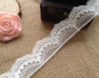 May include: White lace trim with a delicate floral pattern. The lace is on a burlap background.