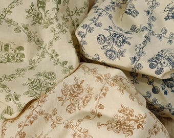 May include: Close-up of four folded fabric pieces with a cream background. Each piece features a different floral and pastoral design in shades of green, brown, and blue. The fabric has a vintage, toile-like aesthetic.