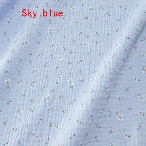 May include: Sky blue fabric with a small white floral pattern. The fabric has a slightly textured surface.
