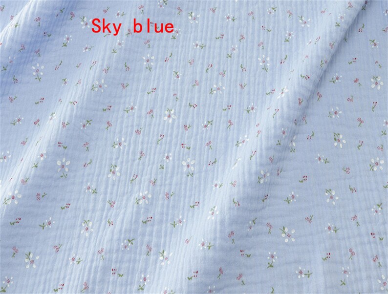 May include: Sky blue fabric with a small white floral pattern. The fabric has a slightly textured surface.