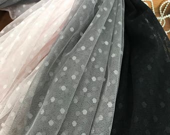 May include: Three layers of tulle fabric with white polka dots. The top layer is a light pink, the middle layer is a light gray, and the bottom layer is black.