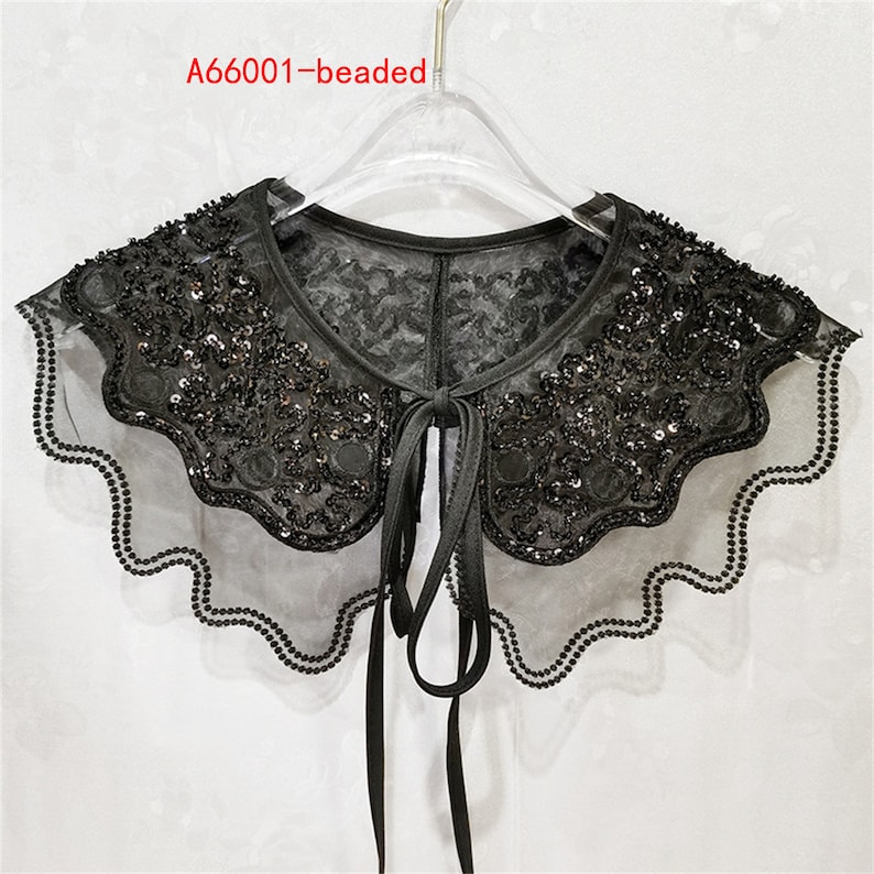 May include: A black beaded lace collar with a scalloped edge and a tie closure. The collar is on a hanger.