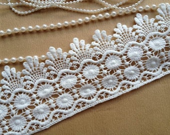 May include: White lace trim with a scalloped edge and a delicate floral pattern. The lace is made of a fine, soft material and has a subtle sheen.