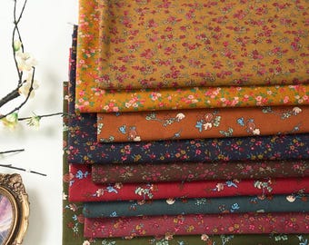 May include: A selection of floral fabric in shades of mustard, rust, navy, and burgundy. Each fabric displays a repeating pattern of small flowers in pink, blue, and green. The fabrics are neatly folded, showcasing the different colour options for crafting or sewing projects.