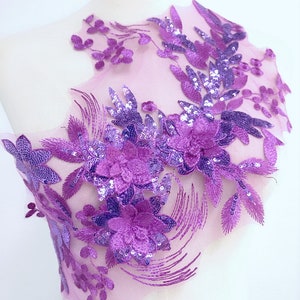 Może przedstawiać: Fioletowy haft kwiatowy z cekinami i koralikami na przezroczystej siatce. Haft przedstawia skupisko kwiatów i liści.