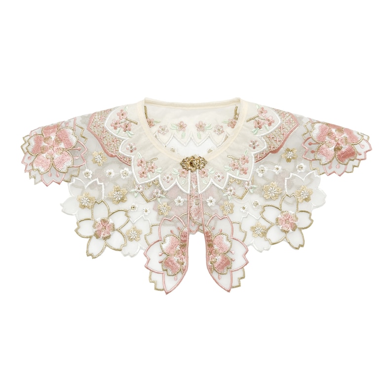 May include: A delicate white lace collar with pink floral embroidery and a gold button accent. The collar is designed to be worn as a fashion accessory.