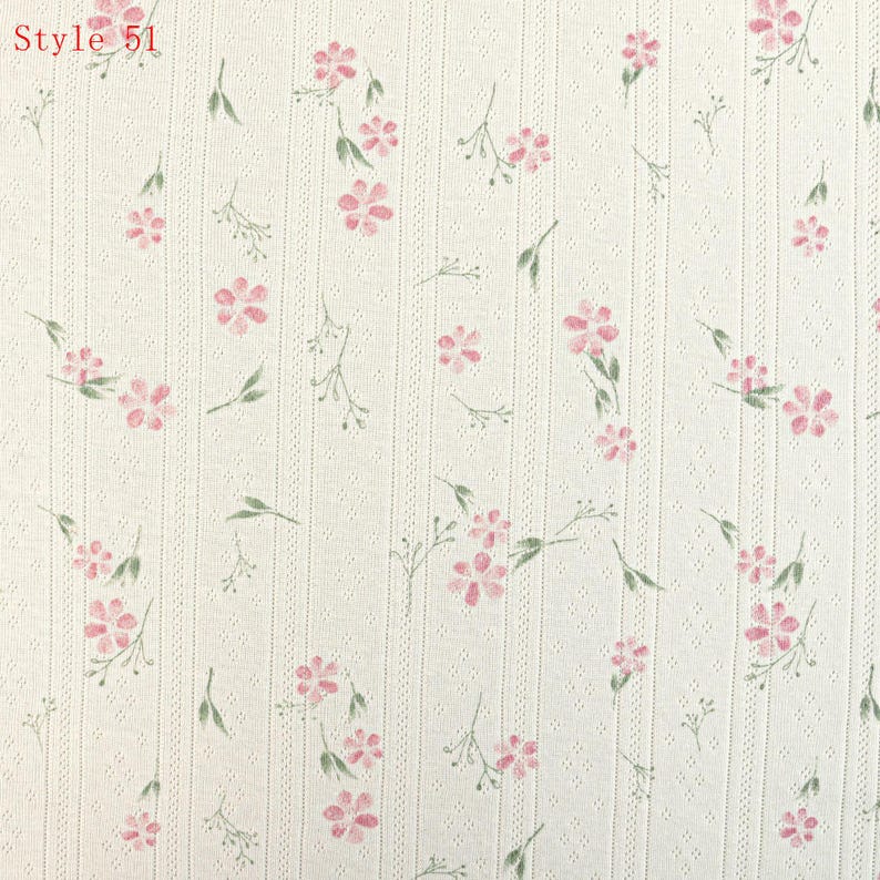 May include: Off-white fabric featuring a vertical ribbed texture with a repeating pattern of small pink flowers and green stems. The text Style 51 is printed in the upper left corner. The material has a subtle, perforated dot pattern.