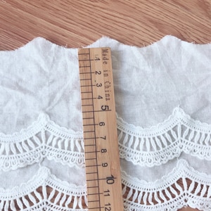 May include: White cotton lace trim with a scalloped edge. The trim is approximately 10 inches long and has a delicate, intricate design. Made in China.
