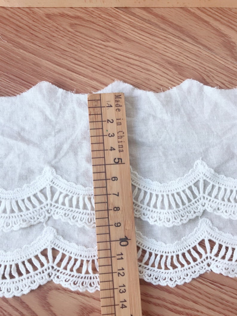 May include: White cotton lace trim with a scalloped edge. The trim is approximately 10 inches long and has a delicate, intricate design. Made in China.
