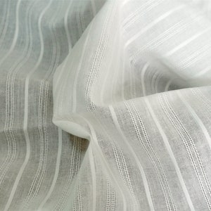 May include: White cotton fabric with thin, vertical stripes. The fabric is woven with a subtle texture and has a soft, drapey feel.