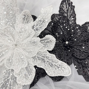 May include: Two large, decorative flower appliques. One is white with a pearl-like finish and the other is black with a beaded finish.