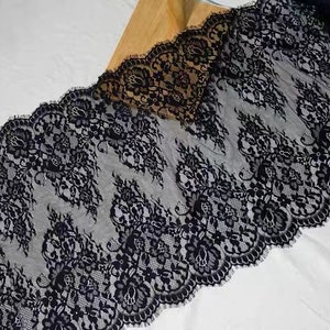 May include: Black lace trim with a delicate floral pattern. The lace is soft and sheer, with a scalloped edge.