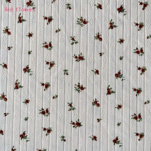 May include: Cream-colored fabric with a vertical ribbed texture and a pattern of small red flowers and green leaves. The text "Red flowers" is in the upper left corner. The floral design is evenly distributed across the fabric.