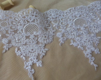 May include: White lace trim with a delicate floral pattern. The lace has a scalloped edge and is perfect for adding a touch of elegance to any project.