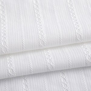 May include: White fabric with a textured, woven pattern. The fabric has vertical stripes and a delicate, raised design.