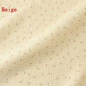 May include: Beige fabric with a small white floral pattern. The fabric has a slightly textured surface.