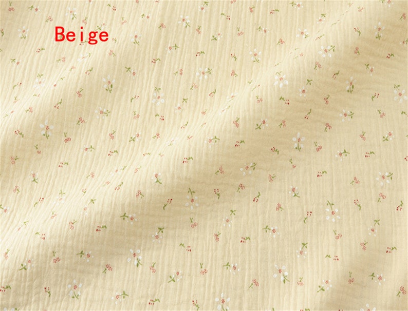 May include: Beige fabric with a small white floral pattern. The fabric has a slightly textured surface.
