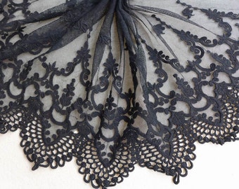 May include: Black lace fabric with a delicate floral pattern. The lace has a scalloped edge and is perfect for adding a touch of elegance to any project.