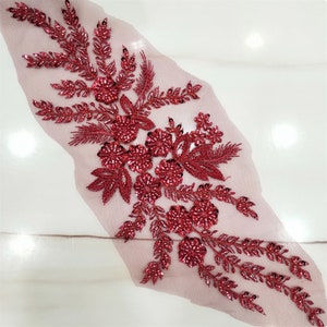 May include: Red beaded floral applique with a mesh backing. The applique features a cluster of flowers and leaves with a beaded design.