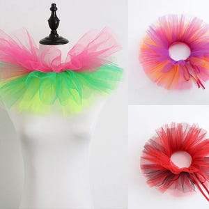May include: A layered tulle neck ruff featuring a vibrant colour palette of pink, green, and yellow. Additional variations include a multi-coloured orange, purple, and pink ruff, and a separate red and black layered tulle neck accessory with ties.