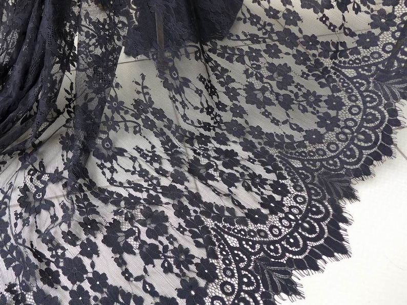 Puede incluir: Tela de encaje negra con un delicado patr&oacute;n floral y bordes festoneados.