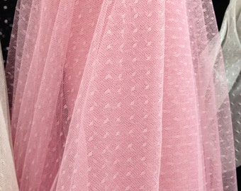 May include: Pink tulle fabric with small white polka dots. The fabric is soft and sheer, and it would be perfect for making a dress, skirt, or other garment.