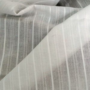 May include: White sheer fabric with thin vertical stripes. The fabric is woven with a subtle texture.