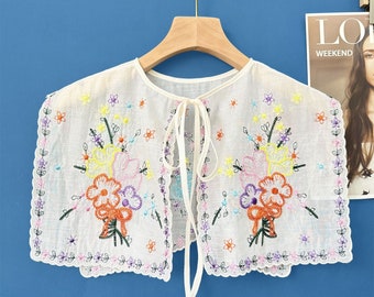 May include: White cotton collar with colourful floral embroidery. The collar has a tie closure at the back.