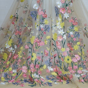 May include: Beige tulle fabric with embroidered floral designs in pink, yellow, white, and green.