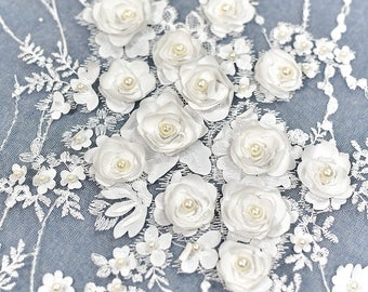 以下が含まれることがあります： 3Dの花とパールがあしらわれた白い花のレース生地。繊細で複雑なデザインで、どんなプロジェクトにもエレガントなアクセントを加えるのに最適です。