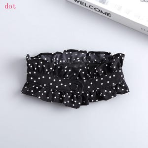 May include: Black and white polka dot ruffled collar with a button closure. The collar is made of a soft fabric and has a delicate, feminine design. The word "dot" is in the top left corner.
