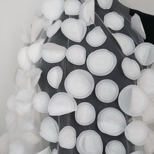Könnte beinhalten: Weißer, durchsichtiger Stoff mit großen, weißen 3D-Kreisen. Die Kreise sind übereinander gelegt und haben eine leicht erhabene Textur.