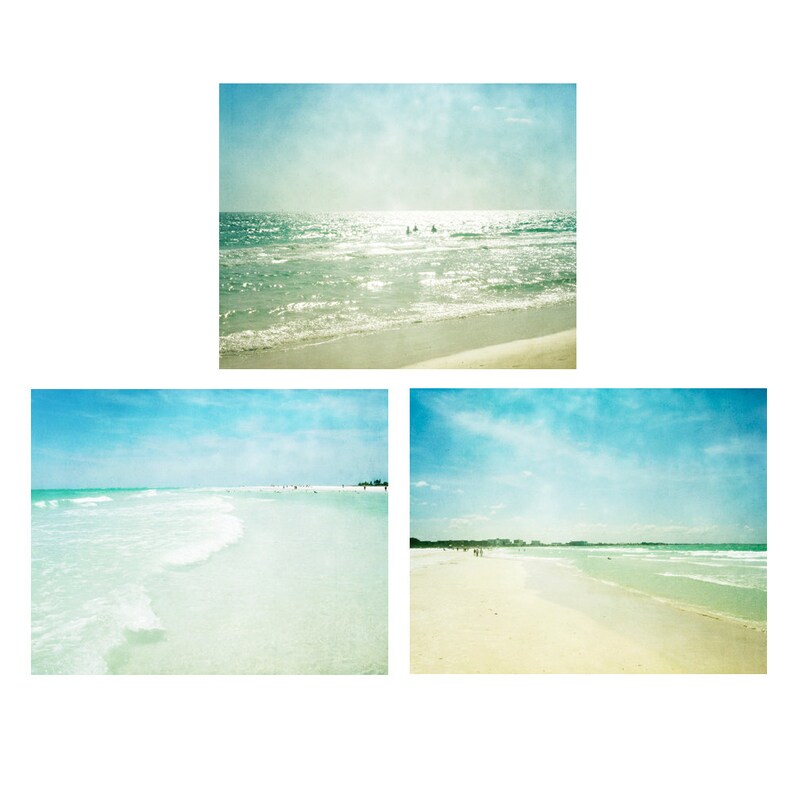 May include: Three photos of a beach with blue skies and white sand. The first photo shows the ocean with waves crashing on the shore. The second photo shows a wide view of the beach with the ocean in the background. The third photo shows a close-up of the sand with the ocean in the background.
