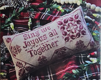May include: A cross-stitch sampler with the text "Sing we Joyous all Together" in a red and white plaid background. The sampler is on a pillow with a red and white plaid fabric.