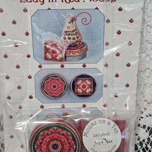 May include: A craft kit titled "Lady in Red Mouse" by Just Nan. The kit includes a cross-stitch pattern with a mouse design, two tins with red floral patterns, and a small red wax block. The packaging is clear plastic.