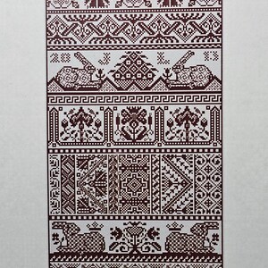 May include: A cross-stitch sampler pattern with the text "LONG DOG SAMPLERS" at the top. The design features various geometric and floral patterns in shades of brown. The text "Hare Apparent" and size details are at the bottom.