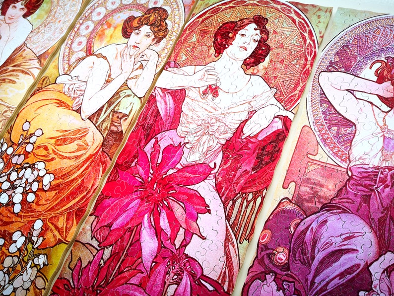 May include: Four vintage art nouveau style jigsaw puzzle pieces featuring women in elaborate dresses and floral designs. The pieces are in shades of pink, red, orange, and yellow.