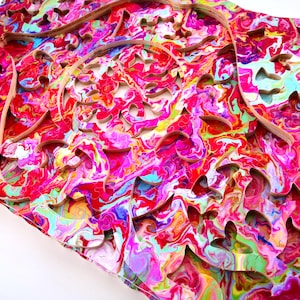 May include: A colorful wooden jigsaw puzzle with a swirling, abstract design. The puzzle pieces are cut in a intricate pattern, creating a unique and challenging puzzle experience.