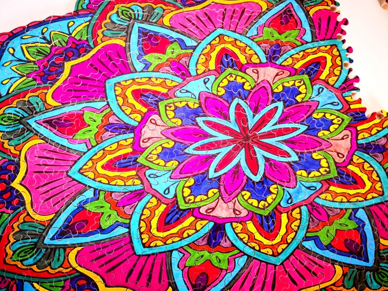 Peut inclure: Un puzzle en bois color&eacute; avec un motif de mandala repr&eacute;sentant une grande fleur au centre. Les pi&egrave;ces du puzzle sont en forme de p&eacute;tales et de feuilles qui s'embo&icirc;tent, cr&eacute;ant un motif complexe. Les couleurs sont vives et comprennent des nuances de rose, de bleu, de jaune, de vert et de rouge.