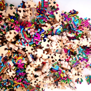 Peut inclure: Un gros plan d'un puzzle color&eacute; avec de nombreuses pi&egrave;ces. Les pi&egrave;ces sont en bois et pr&eacute;sentent une vari&eacute;t&eacute; de motifs abstraits. Le puzzle est en cours d'assemblage.
