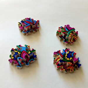 Peut inclure: Quatre piles de pi&egrave;ces de puzzle color&eacute;es avec des motifs complexes. Chaque pile est compos&eacute;e de plusieurs pi&egrave;ces, cr&eacute;ant un effet de superposition. Les pi&egrave;ces sont dispos&eacute;es en forme carr&eacute;e, chaque pile &eacute;tant l&eacute;g&egrave;rement d&eacute;cal&eacute;e par rapport &agrave; la suivante.
