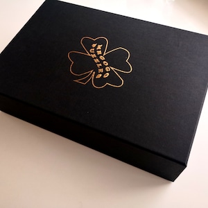 May include: A black box with a gold four-leaf clover design and the text "MRGOGG PUZZLE" on the top.