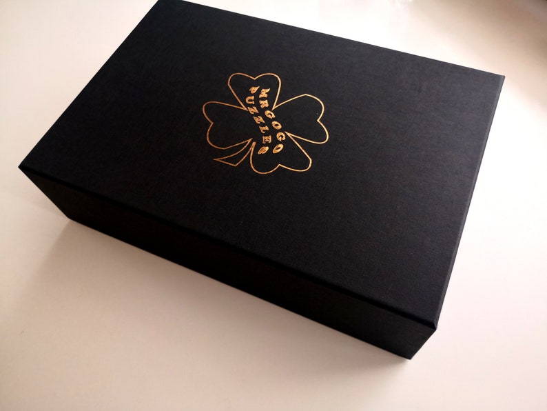 May include: A black box with a gold four-leaf clover design and the text "MRGOGG PUZZLE" on the top.