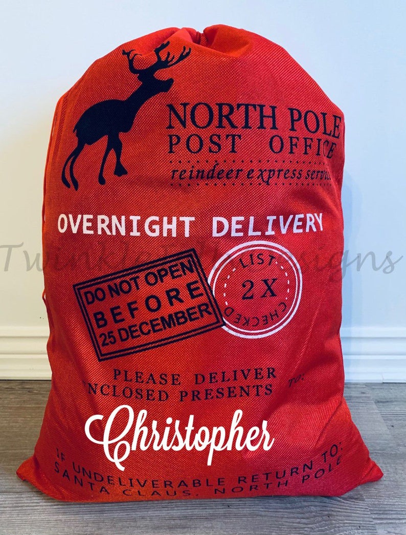 May include: Red Christmas gift sack with a black reindeer silhouette and the words "North Pole Post Office" and "Overnight Delivery." The sack includes the name "Christopher" in white script and a "Do Not Open Before 25 December" stamp.