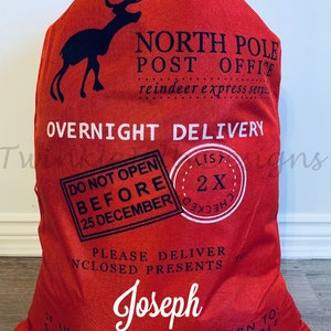 May include: Red Christmas gift sack with a black reindeer silhouette and the text "North Pole Post Office." The sack includes the text "Overnight Delivery" and "Do Not Open Before 25 December." The name "Joseph" is printed on the sack.