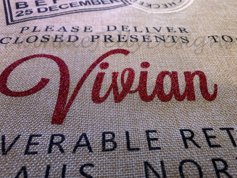 May include: Close-up of a burlap fabric with the name "Vivian" in red glitter script. The text "PLEASE DELIVER CLOSED PRESENTS TO" and other phrases are printed in black, with a stamp graphic at the top. The theme is gift delivery.