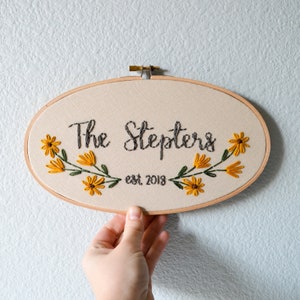 May include: Embroidered hoop with the text "The Stepters est. 2013" surrounded by yellow and green flowers.
