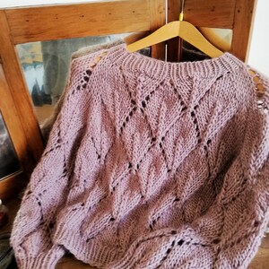 K&ouml;nnte beinhalten: Ein weicher, mauvefarbener Strickpullover mit einem zarten Lochmuster. Der Pullover hat eine lockere Passform und lange &Auml;rmel.